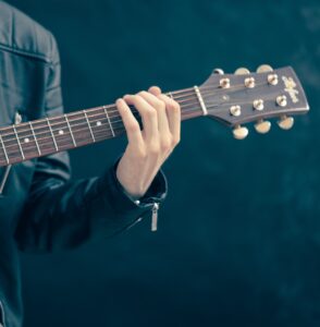 En gitarist som håller i en gitarr. Endast vänster arm på bild.